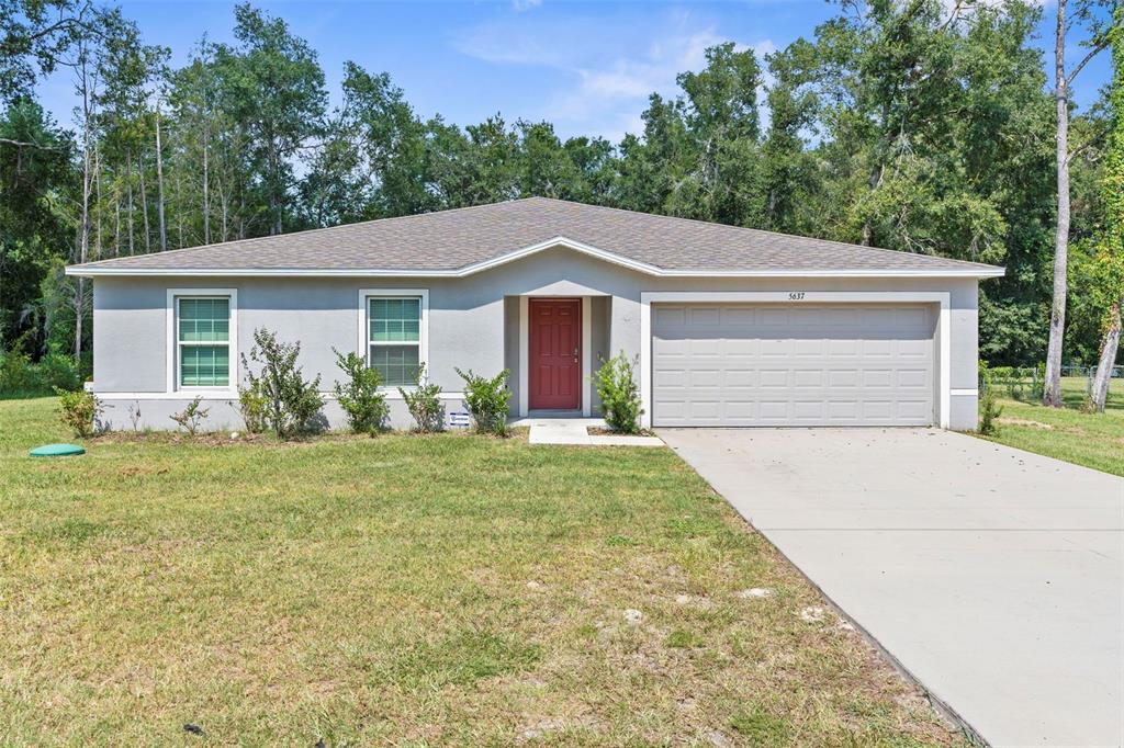 A single-story house with a gray exterior, red front door, and an attached two-car garage — 5637 E TANGELO LANE, INVERNESS, FL