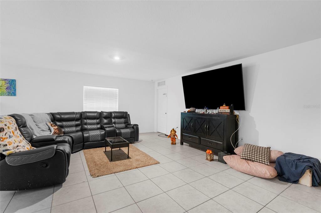 A living room features a large black sectional sofa, a television on a console, and tile flooring — 5637 E TANGELO LANE, INVERNESS, FL