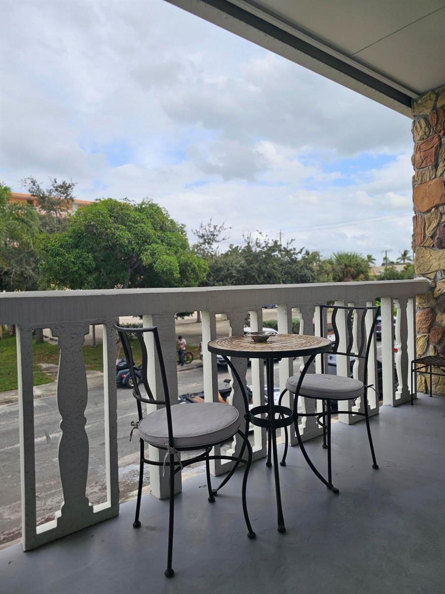A balcony features a small bistro set with two chairs overlooking a street and trees — 17 S Lakeside Drive # 4, FL 33460, FL
