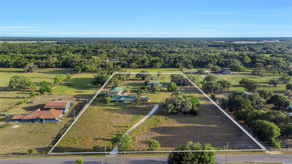An aerial view shows a house on a large, fenced lot with trees and grass — 20138 BOWMAN ROAD, SPRING HILL, FL