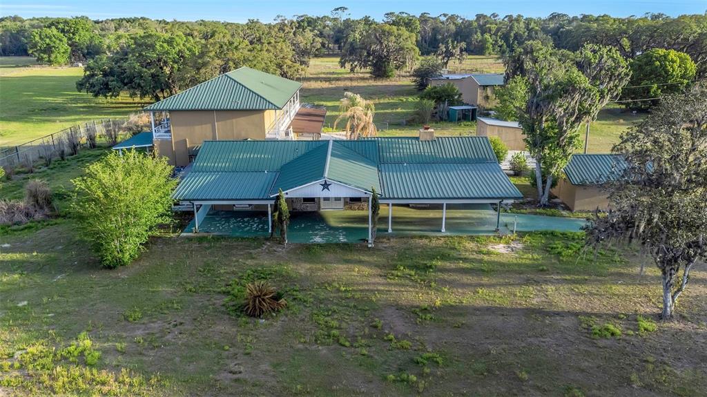An aerial view shows a two-story house with a green metal roof and porch — 20138 BOWMAN ROAD, SPRING HILL, FL