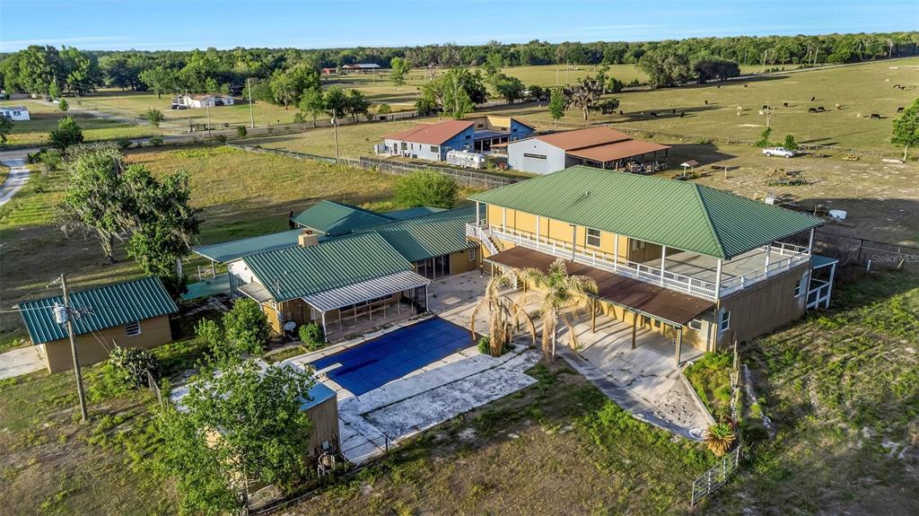 An aerial view shows a house with a green metal roof and a swimming pool — 20138 BOWMAN ROAD, SPRING HILL, FL