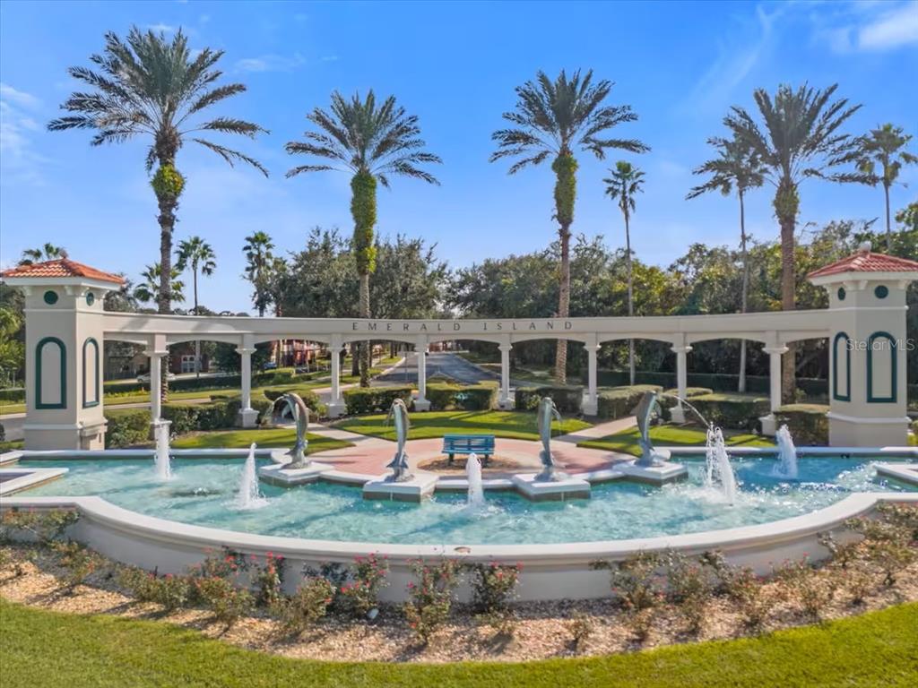 A decorative fountain with dolphin statues sits in front of the Emerald Island entrance gate — 8515 CRYSTAL COVE LOOP, KISSIMMEE, FL