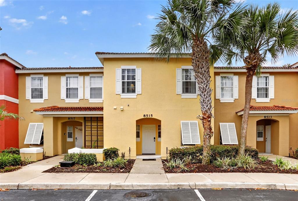 A row of three attached townhouses with yellow stucco walls and white shutters — 8515 CRYSTAL COVE LOOP, KISSIMMEE, FL