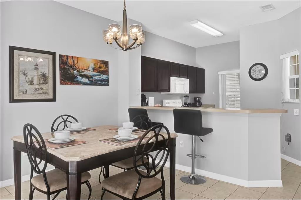 A dining area with a table and chairs sits adjacent to a kitchen with dark cabinets — 8515 CRYSTAL COVE LOOP, KISSIMMEE, FL