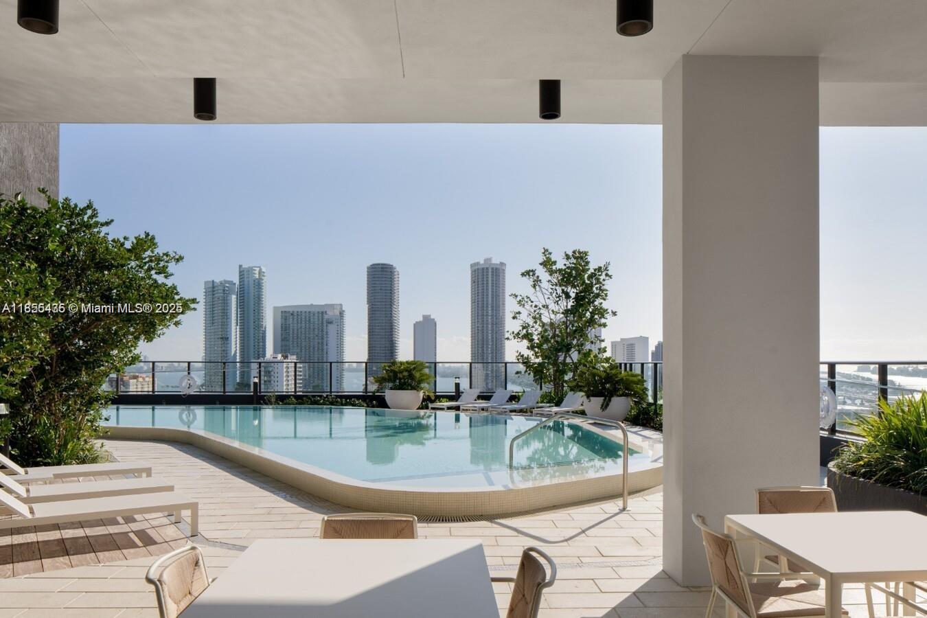 A rooftop swimming pool overlooks a city skyline from a covered outdoor patio area — 23 NE 17th Ter # D1, Miami FL 33132, MIAMI, FL