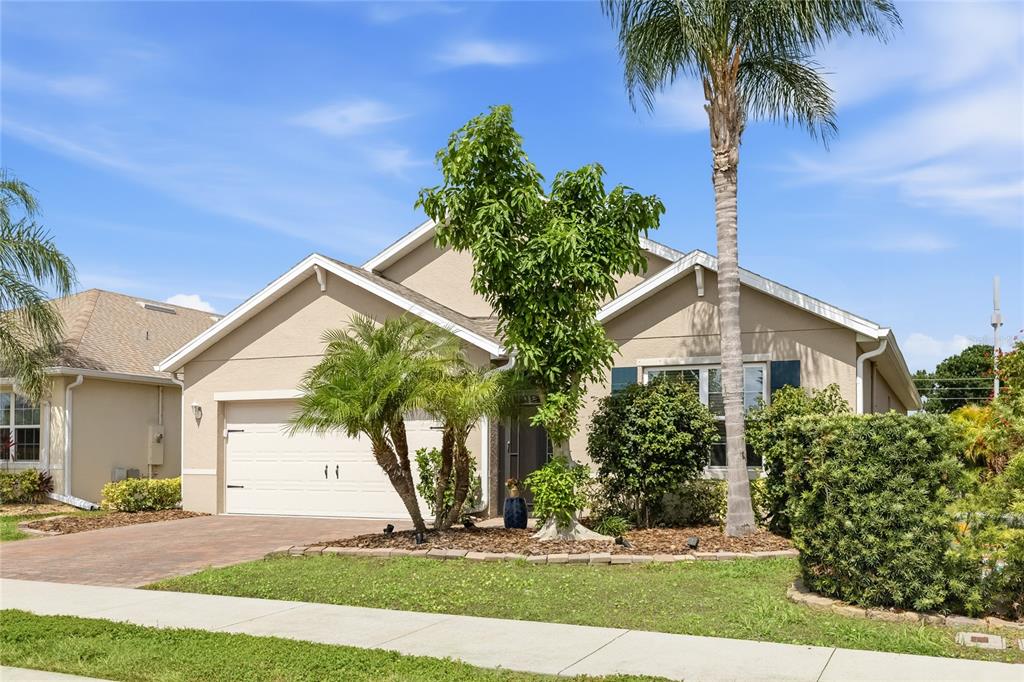 A single-story suburban house with a two-car garage, palm trees, and a landscaped front yard — 24413 BANDONI PLACE, VENICE, FL