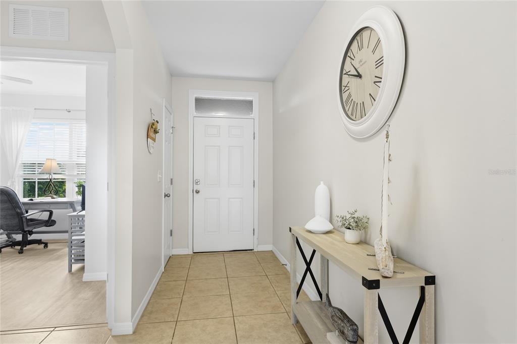 A bright entryway features tile flooring, a white front door, and a console table — 24413 BANDONI PLACE, VENICE, FL