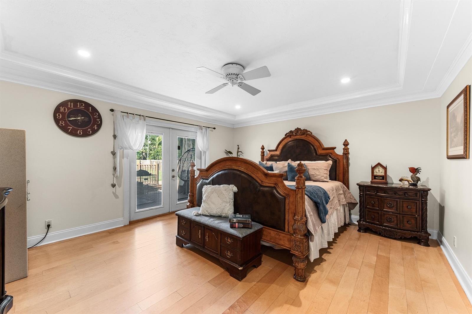 A bedroom features a large wooden bed, a storage bench, and glass doors leading outside — 6567 Cindi Lane, FL 33467, FL