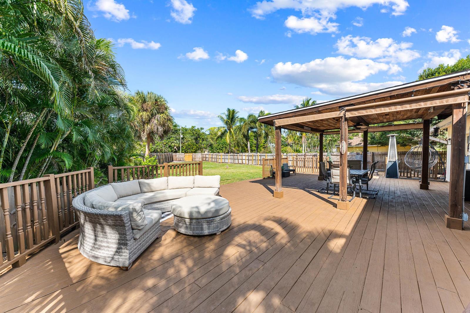 A spacious wooden deck features a curved sectional sofa, a covered patio area, and fencing — 6567 Cindi Lane, FL 33467, FL
