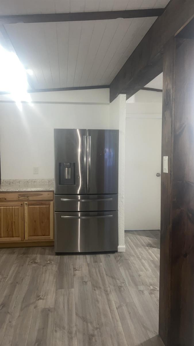 A stainless steel refrigerator stands next to wood cabinets and a granite countertop in a kitchen — 1515 NE 342nd Trail, Okeechobee FL 34972, OKEECHOBEE, FL