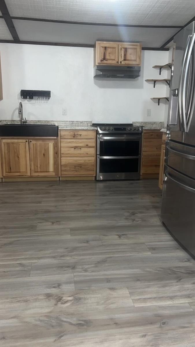 A kitchen features light wood cabinets, stainless steel appliances, a black sink, and gray flooring — 1515 NE 342nd Trail, Okeechobee FL 34972, OKEECHOBEE, FL