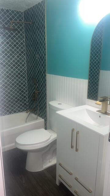 A bathroom features a teal wall, white wainscoting, a patterned tile shower, and gold fixtures — 1515 NE 342nd Trail, Okeechobee FL 34972, OKEECHOBEE, FL