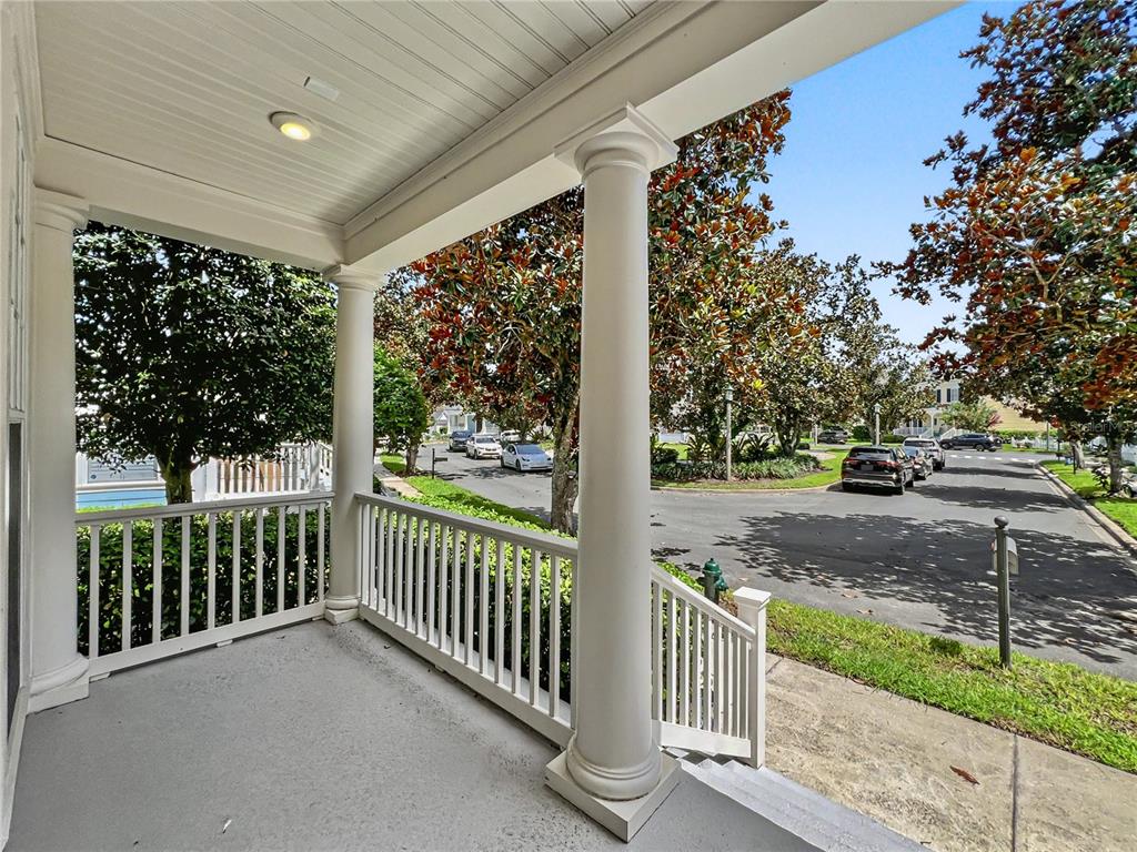 A covered front porch with white columns and railings overlooks a suburban street — 1006 SANDLACE COURT, CELEBRATION, FL