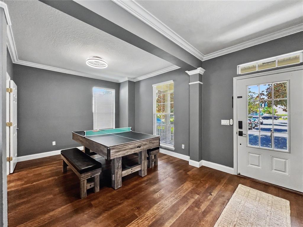 A room with gray walls, hardwood floors, and a game table near the front door — 1006 SANDLACE COURT, CELEBRATION, FL