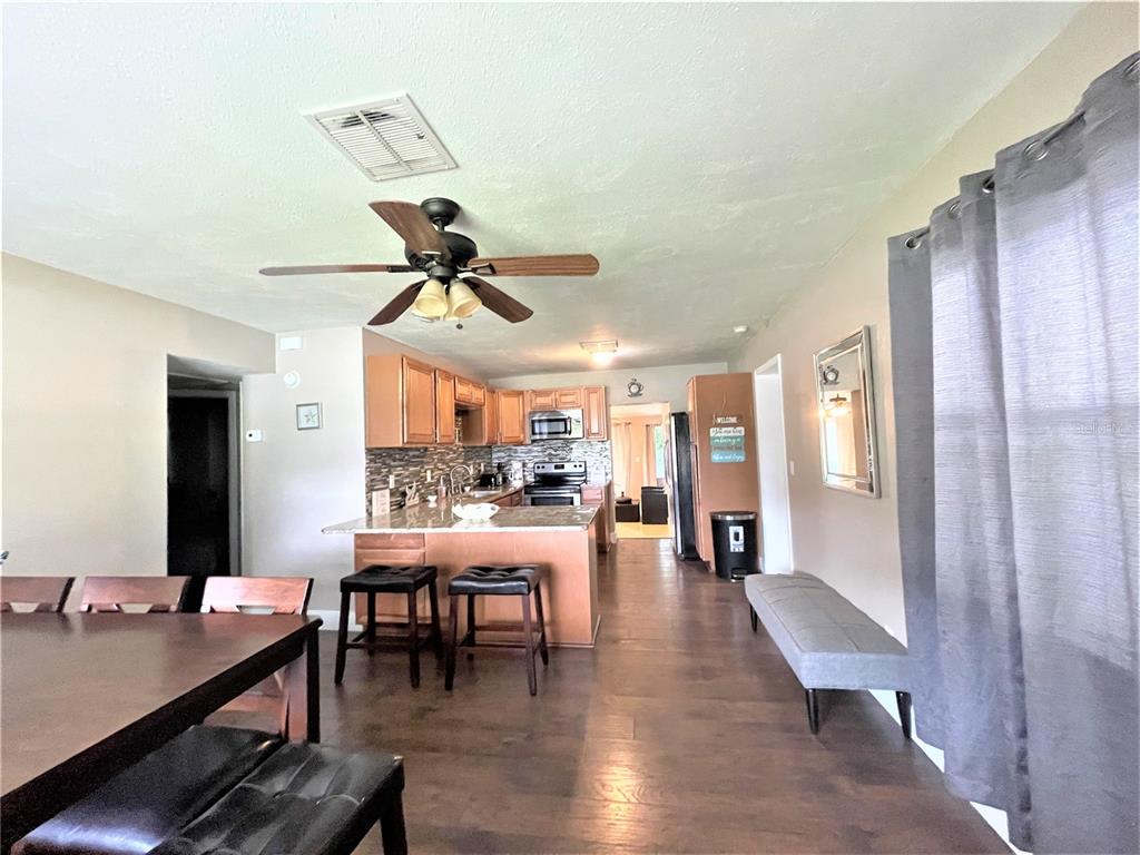 A kitchen with wood cabinets and a breakfast bar opens into a dining area — 5106 104TH STREET N, ST PETERSBURG, FL