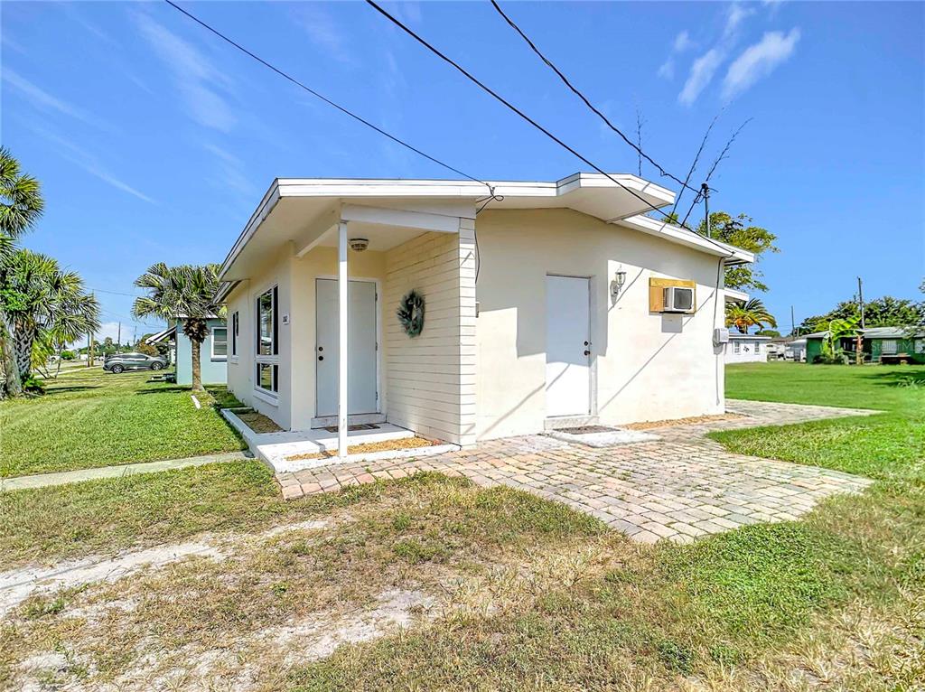 A small, light-colored house with a covered entryway and a brick patio — 21362 HEPNER AVENUE, PORT CHARLOTTE, FL