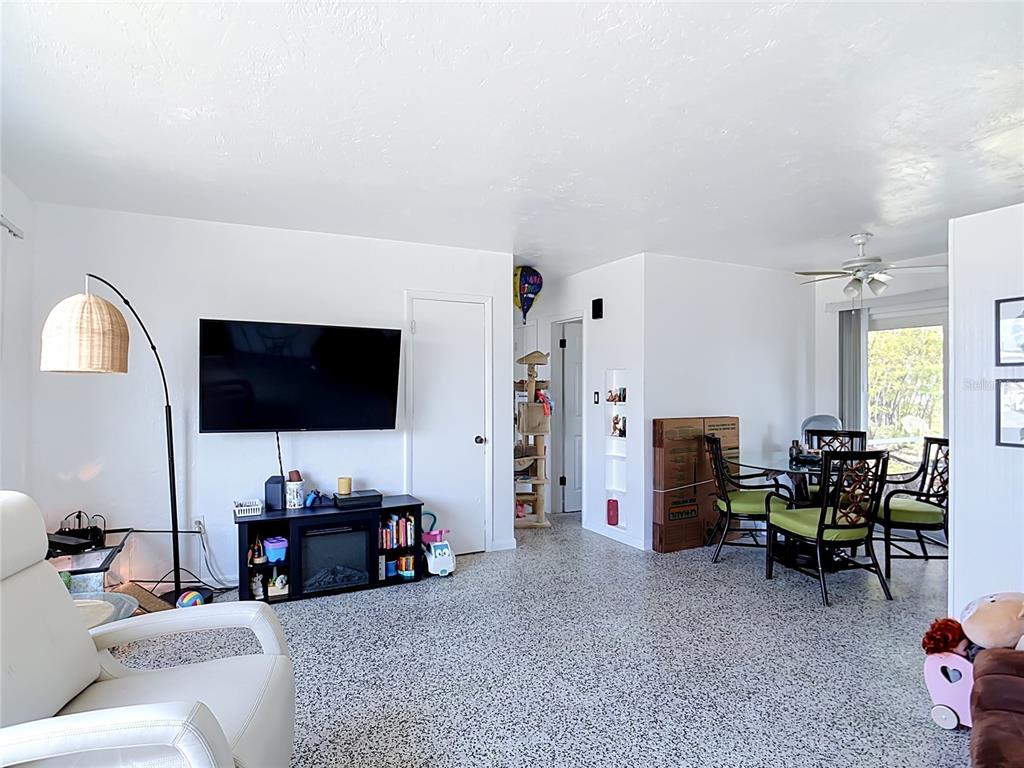 A living and dining area features white walls, a speckled floor, and a mounted television — 21362 HEPNER AVENUE, PORT CHARLOTTE, FL
