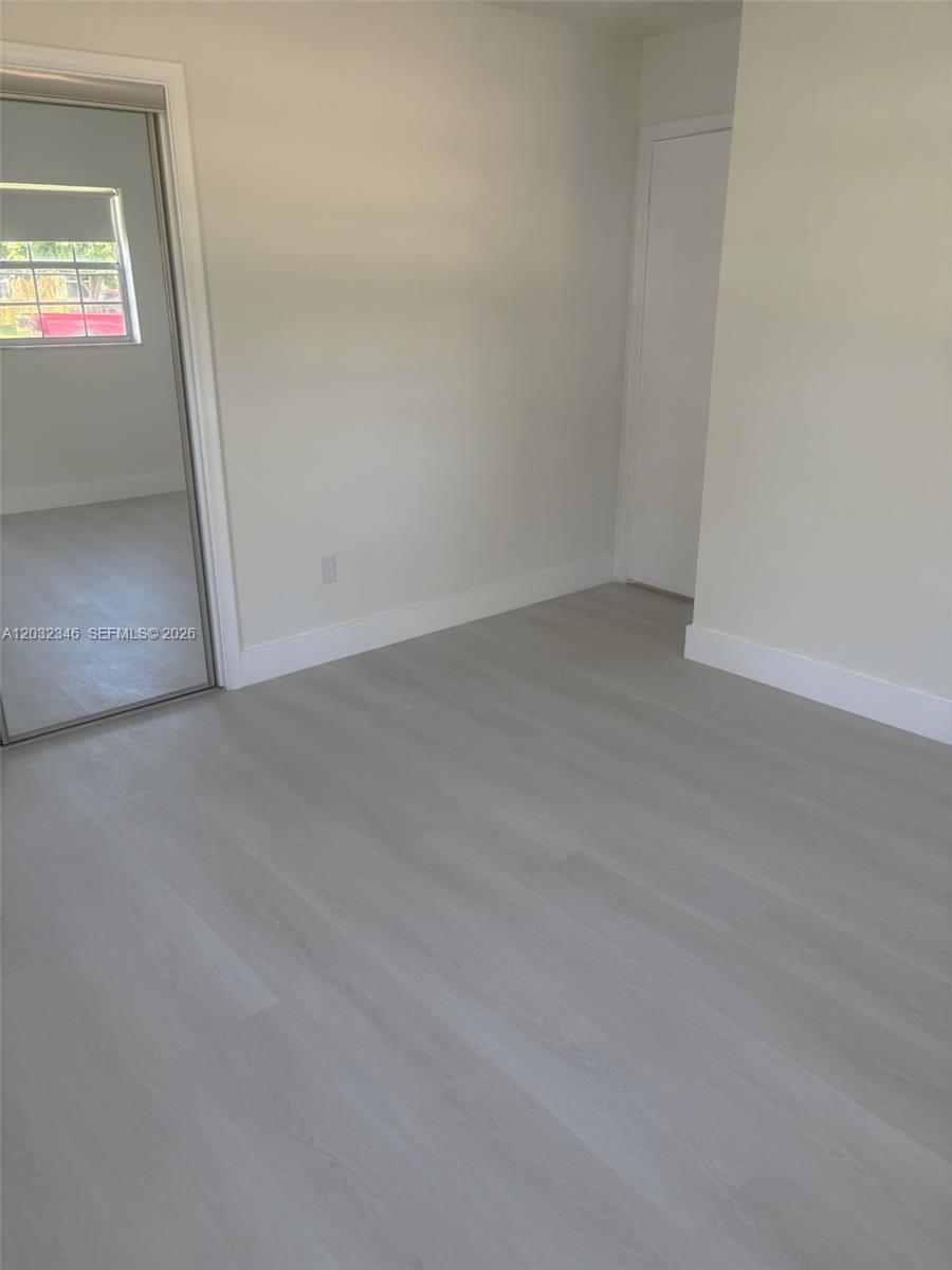 An empty room features light-colored wood-look flooring, white walls, and a mirrored closet door — 22745 SW 65th Way # 0, Boca Raton FL 33428, BOCA RATON, FL