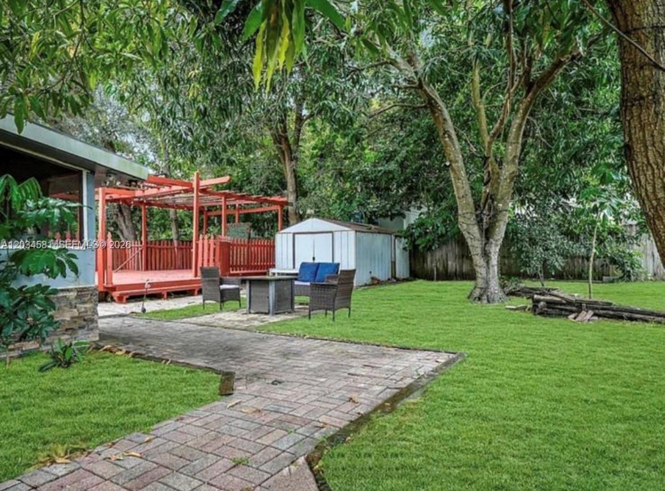 A backyard features a brick walkway, a red wooden pergola, patio furniture, and a storage shed — 2735 Dewey St, Hollywood FL 33020, HOLLYWOOD, FL