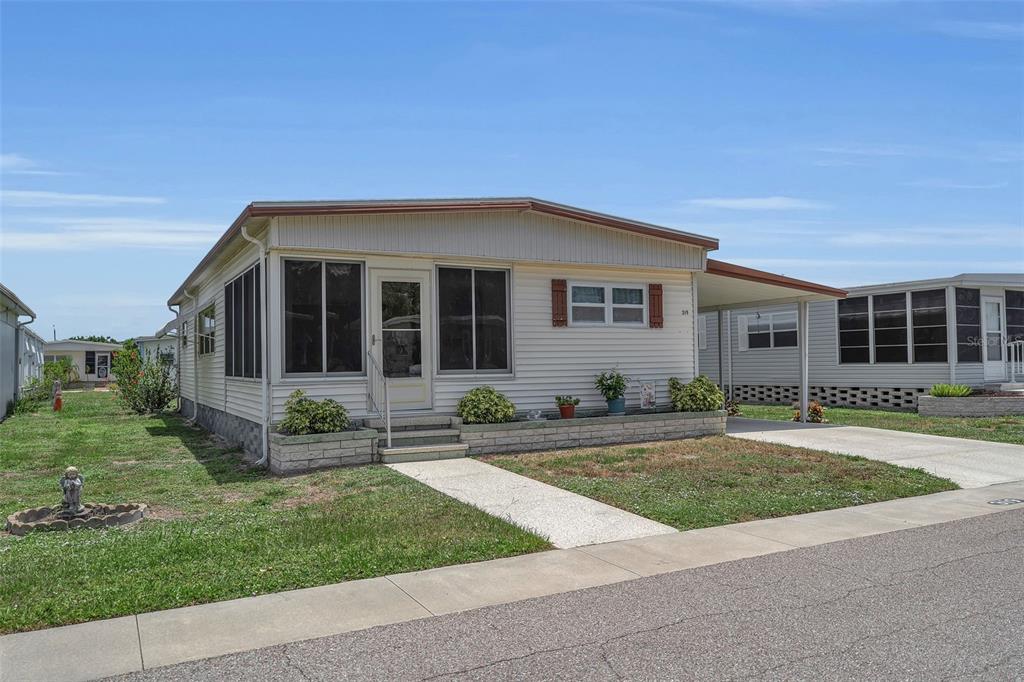 A single-story manufactured home with light siding, a front porch, and an attached carport — 5619 BAYSHORE ROAD UNIT 319, PALMETTO, FL