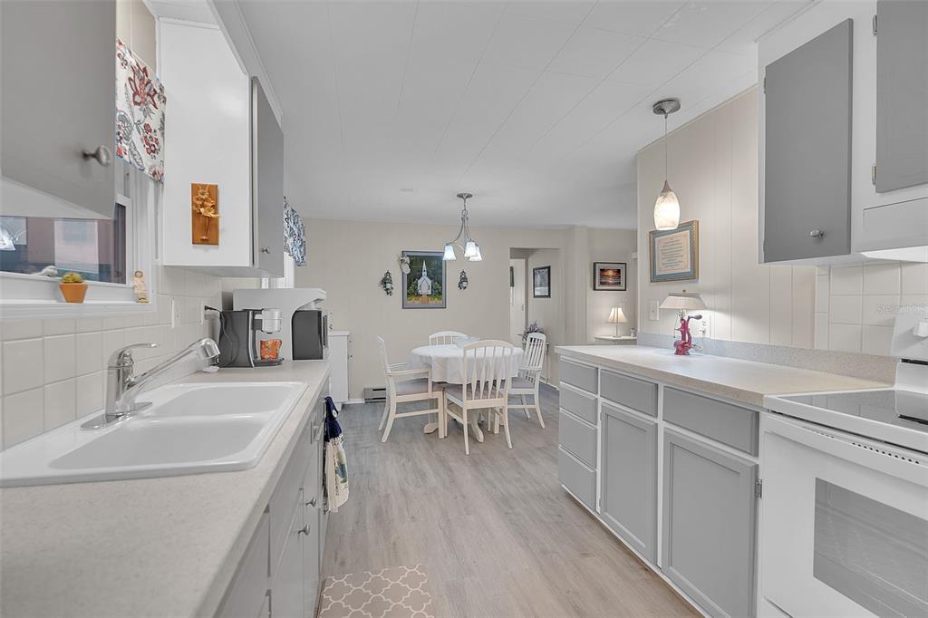 A kitchen with gray cabinets, white countertops, and a dining area with a round table — 5619 BAYSHORE ROAD UNIT 319, PALMETTO, FL