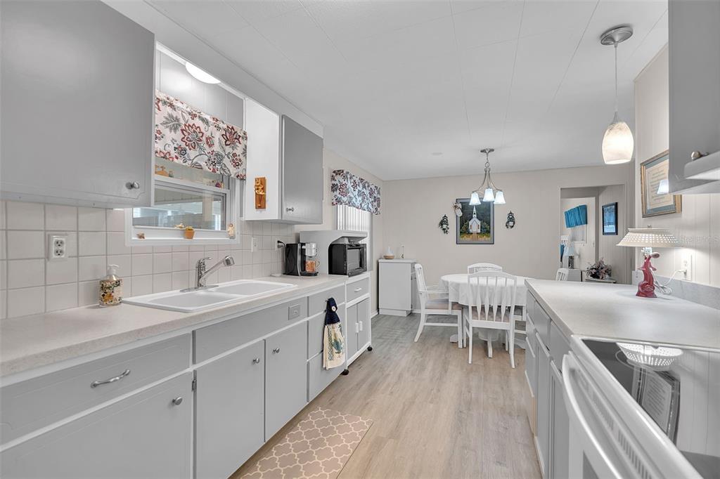 A kitchen with grey cabinets, white countertops, and a dining area with a round table — 5619 BAYSHORE ROAD UNIT 319, PALMETTO, FL