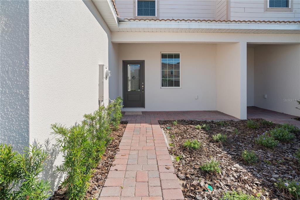 A paved walkway leads to the front entrance of a house with a covered porch — 563 BAY LEAF DRIVE, KISSIMMEE, FL