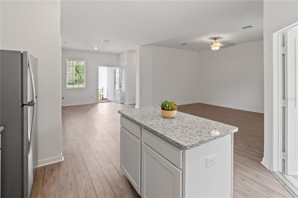 A kitchen island with a granite countertop sits in front of an open-concept living area — 563 BAY LEAF DRIVE, KISSIMMEE, FL