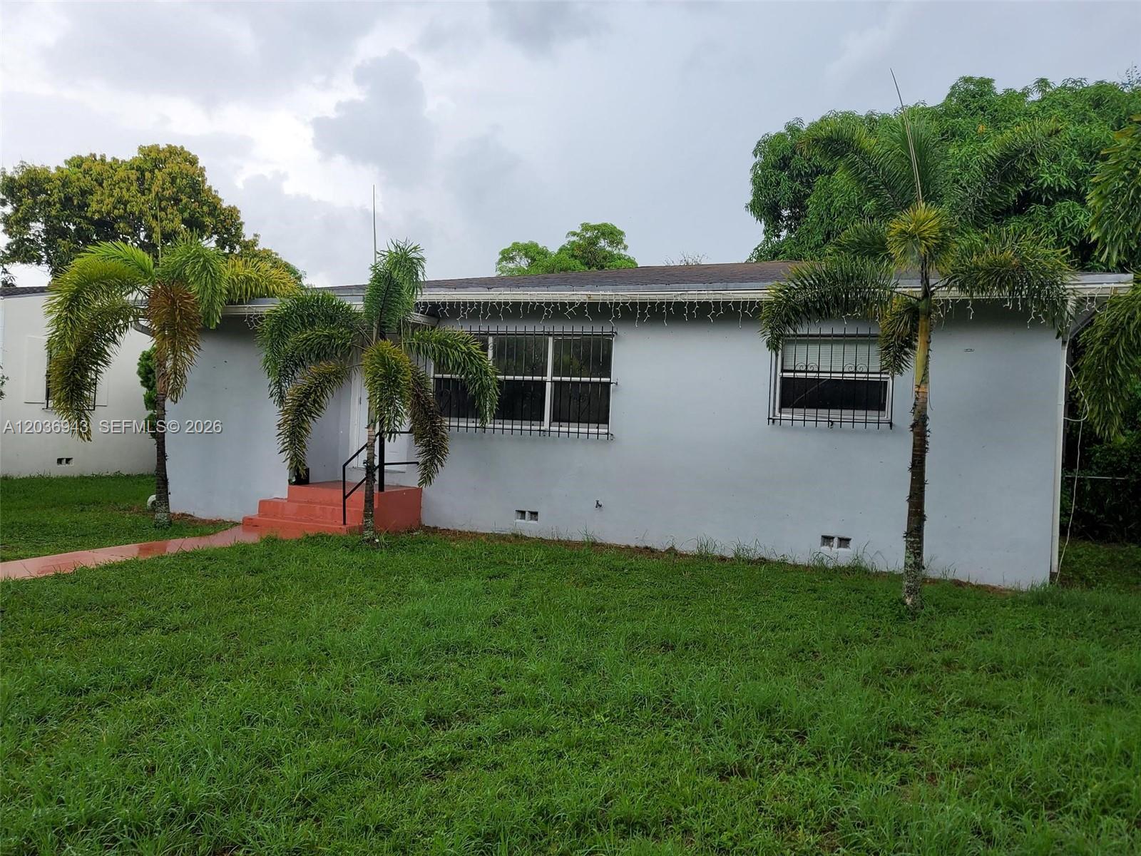 A single-story house with a light gray exterior, palm trees, and security bars on windows — 1225 NW 127th St, North Miami FL 33167, NORTH MIAMI, FL