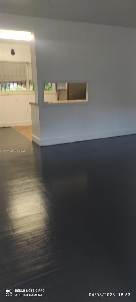 A room with dark flooring features a white wall with a rectangular pass-through window — 1225 NW 127th St, North Miami FL 33167, NORTH MIAMI, FL