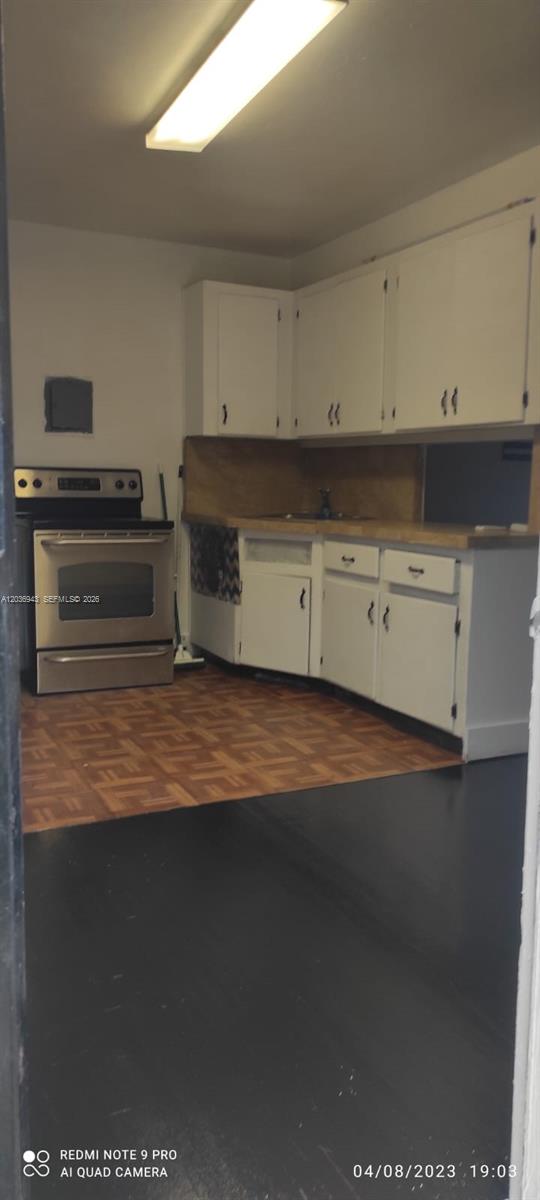A kitchen features white cabinets, a stainless steel stove, and a wood-patterned floor — 1225 NW 127th St, North Miami FL 33167, NORTH MIAMI, FL