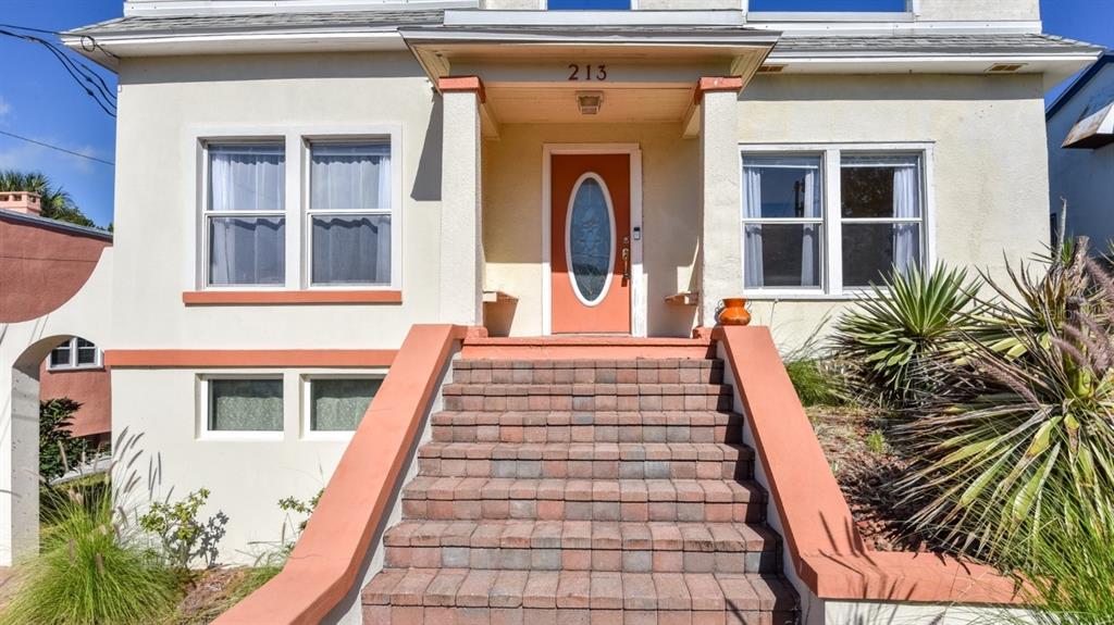 A set of brick stairs leads to the orange front door of a raised house — 213 JESSAMINE BOULEVARD, DAYTONA BEACH, FL