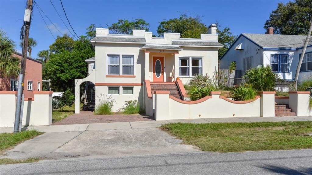 A two-story stucco house with a flat roof, orange door, and a low front wall — 213 JESSAMINE BOULEVARD, DAYTONA BEACH, FL