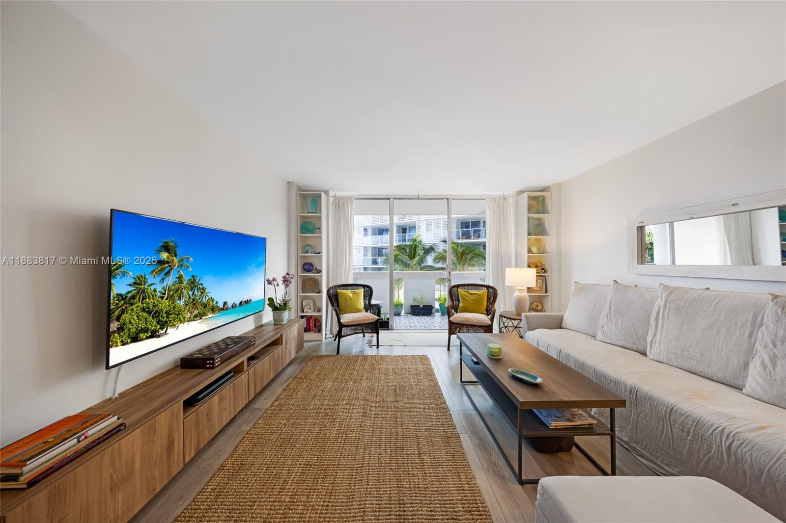 A living room features a large television, a long wooden console, and a balcony view — 800 West Ave # 338, Miami Beach FL 33139, MIAMI BEACH, FL