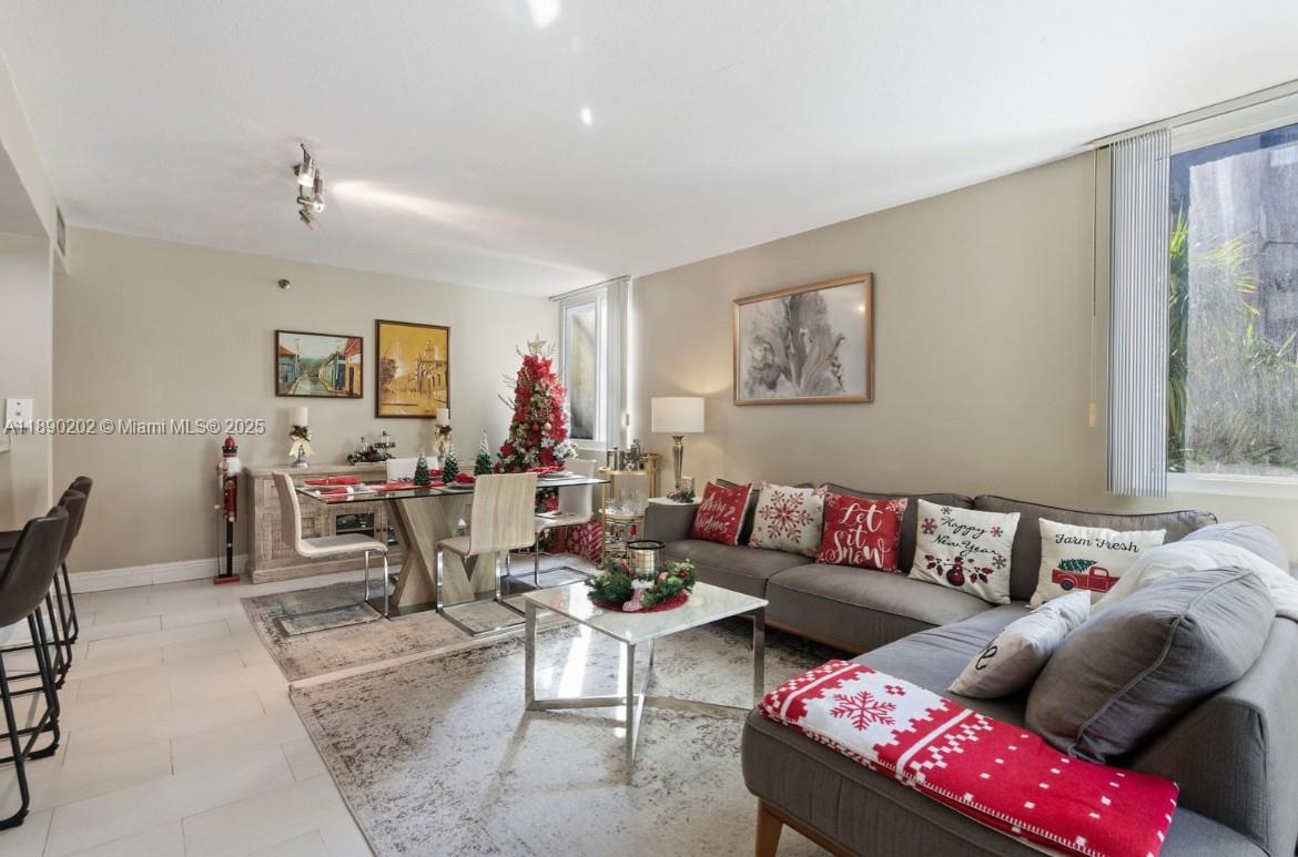 A living and dining room area features a gray sectional sofa, dining table, and decorations — 800 N Miami Ave # 209, Miami FL 33136, MIAMI, FL