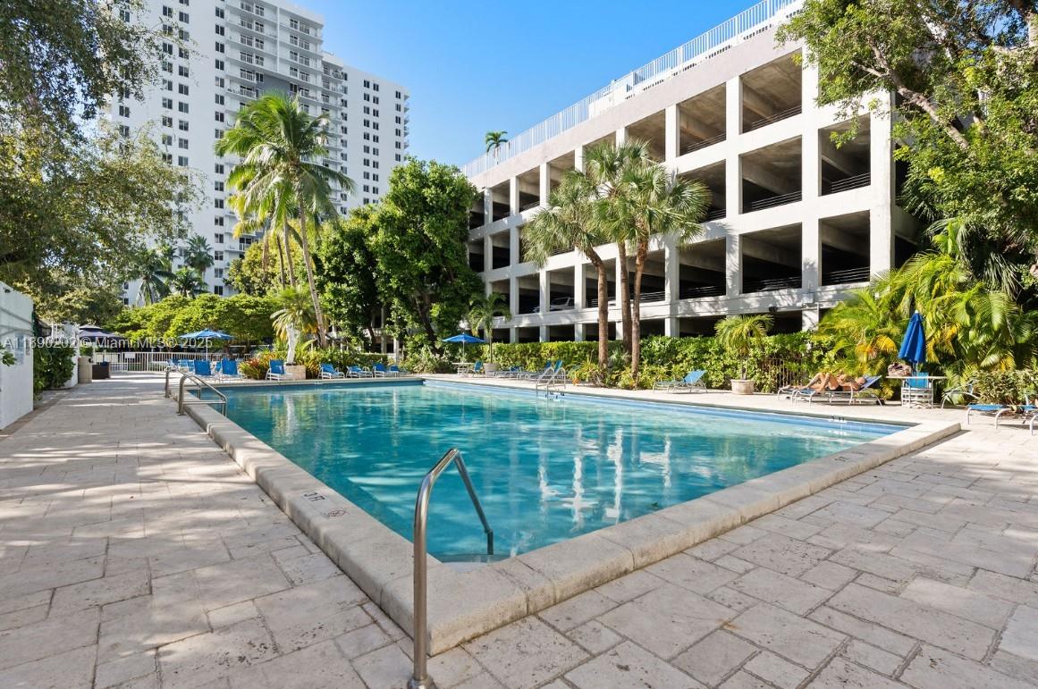 An outdoor swimming pool surrounded by a stone deck, palm trees, and a parking structure — 800 N Miami Ave # 209, Miami FL 33136, MIAMI, FL