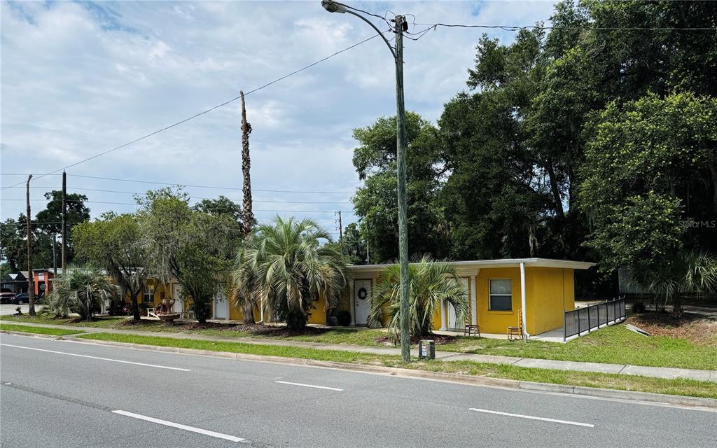 A single-story yellow building sits along a road with palm trees and mature trees — 4851 US HIGHWAY 17 HIGHWAY, DE LEON SPRINGS, FL