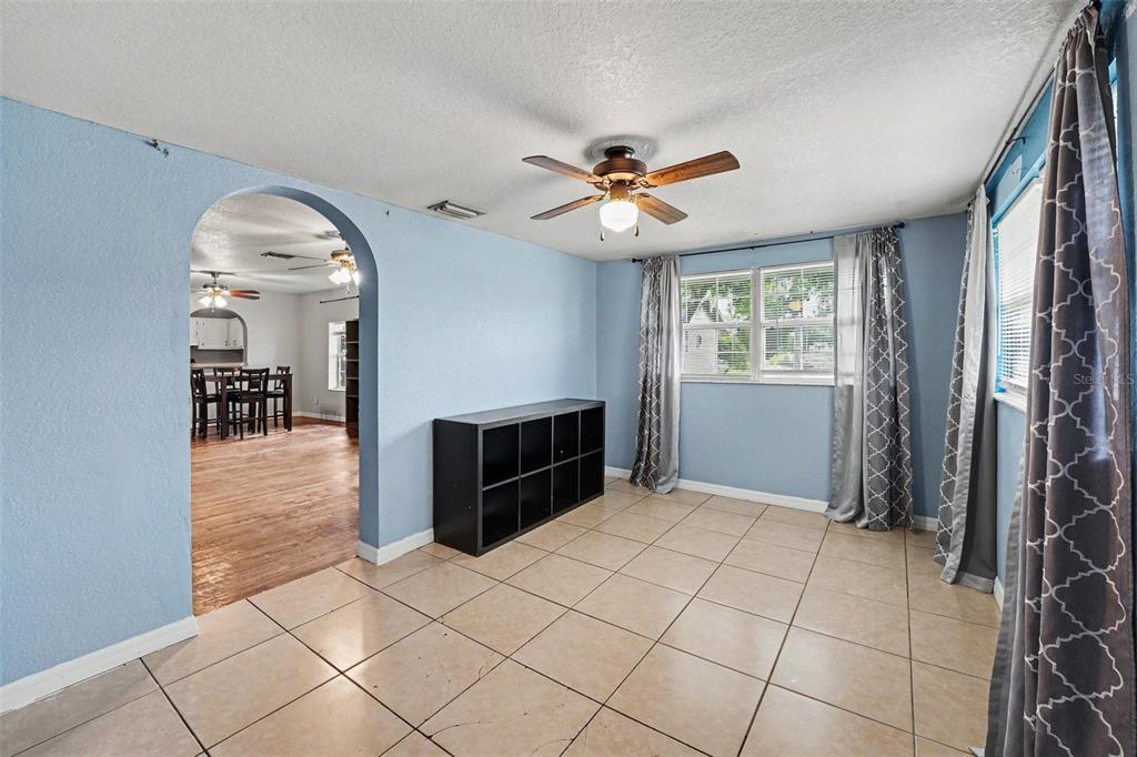 A room with light blue walls, tile flooring, a ceiling fan, and a window with curtains — 406 NW PHOSPHATE BOULEVARD, MULBERRY, FL