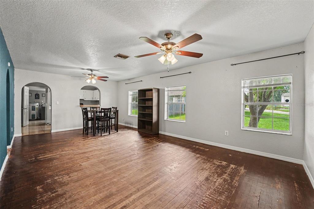 A living room with light blue walls, tile flooring, an arched doorway, and a ceiling fan — 406 NW PHOSPHATE BOULEVARD, MULBERRY, FL