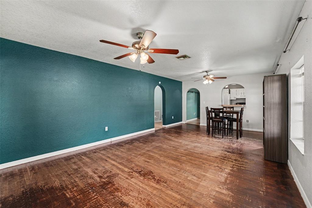 A living room with hardwood floors, two ceiling fans, and an arched doorway to a kitchen — 406 NW PHOSPHATE BOULEVARD, MULBERRY, FL