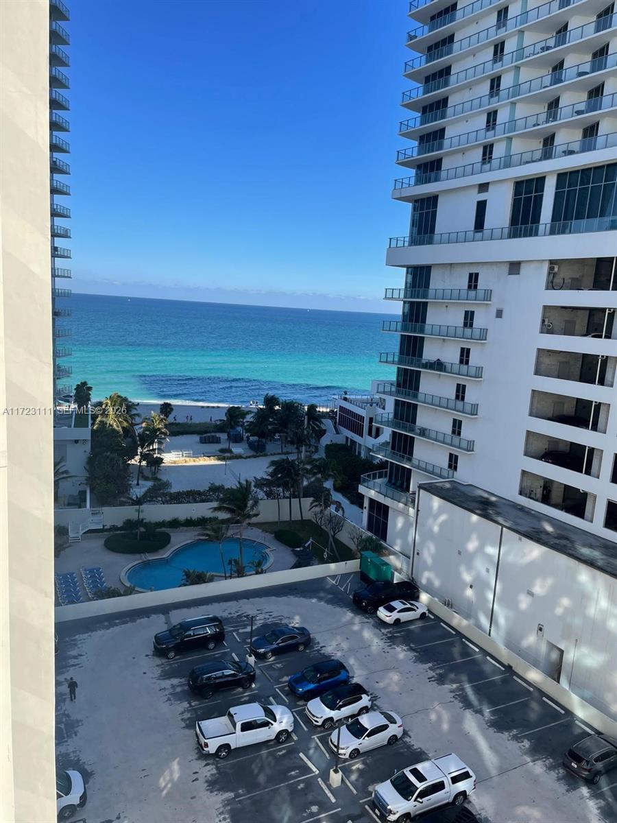 An elevated view shows a parking lot, a swimming pool, and the ocean beyond buildings — 4001 S Ocean Dr # 10D, Hollywood FL 33019, HOLLYWOOD, FL