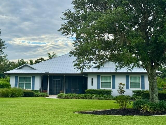 A single-story house with a metal roof and a large tree in the front yard — 15409 29TH LANE E, PARRISH, FL