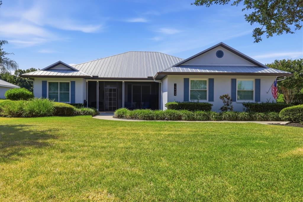 A single-story house with a metal roof, blue shutters, and a screened-in front porch — 15409 29TH LANE E, PARRISH, FL