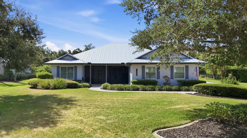 A single-story house with a metal roof, gray siding, and a screened-in front entryway — 15409 29TH LANE E, PARRISH, FL