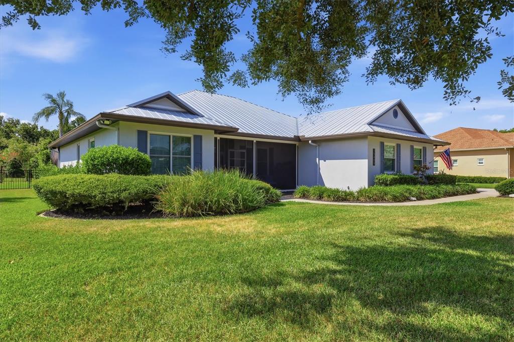 A single-story house with a metal roof, a screened-in porch, and a manicured lawn — 15409 29TH LANE E, PARRISH, FL