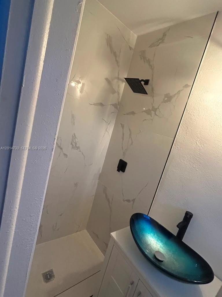 A bathroom features a walk-in shower with marble-look tile and a blue glass vessel sink — 19360 NW 1st Ct, Miami Gardens FL 33169, MIAMI GARDENS, FL