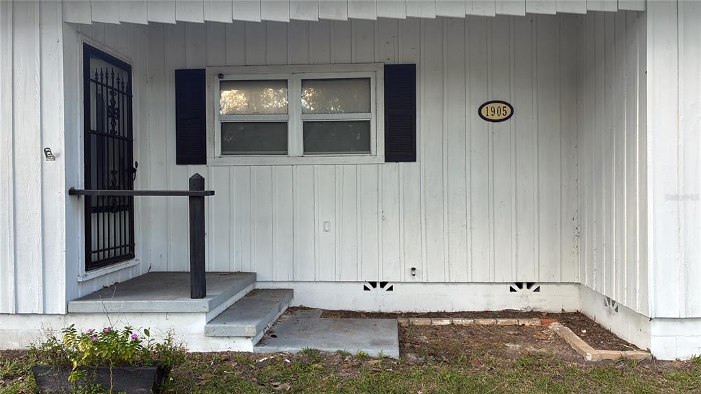 The exterior of a house features white vertical siding, a window with shutters, and steps — 1905 EMMETT STREET, KISSIMMEE, FL