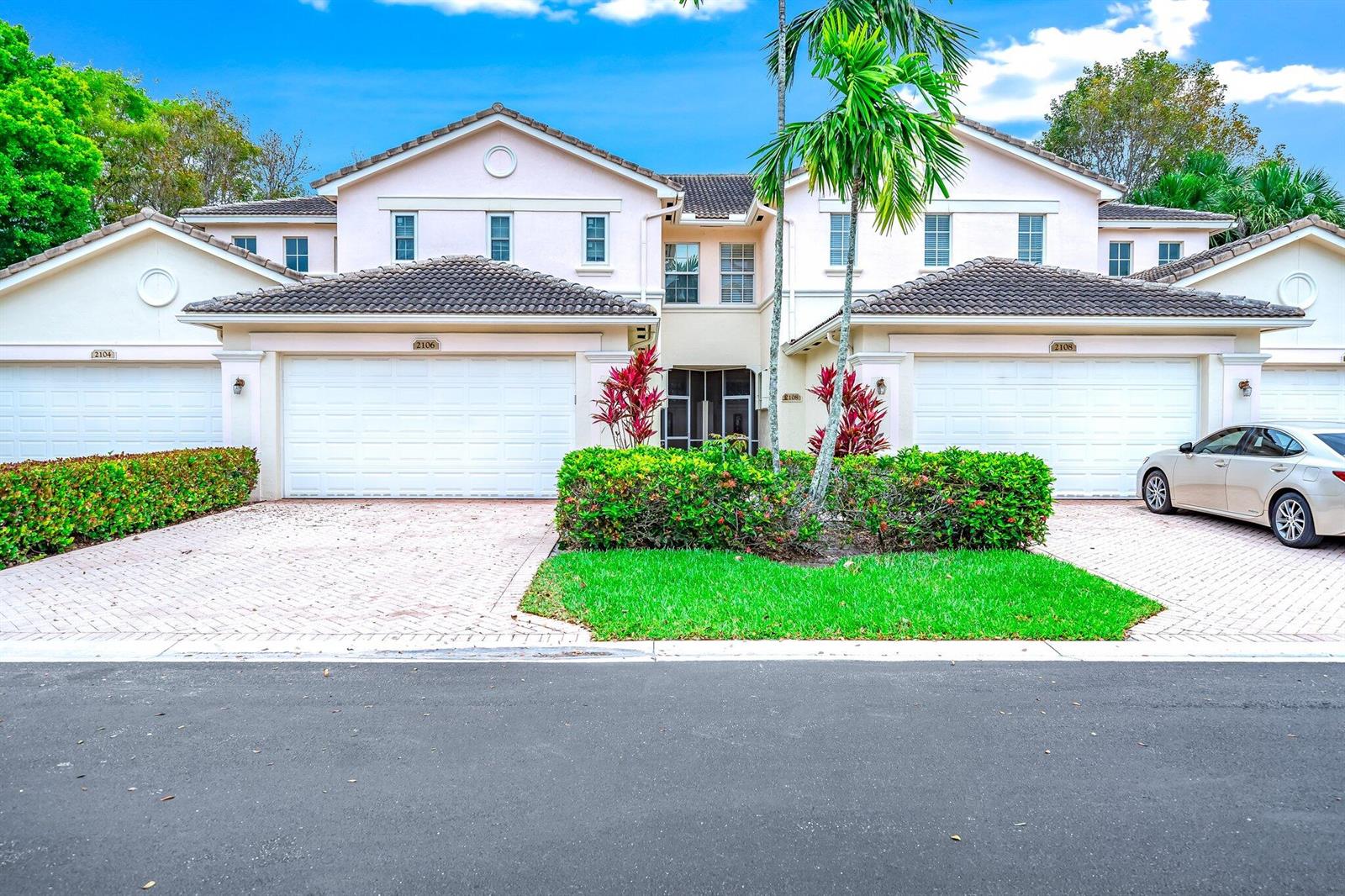 A two-story residential building with two garage doors, a paved driveway, and landscaped front yard — 2106 Wingate Bend, Wellington FL 33414, WELLINGTON, FL