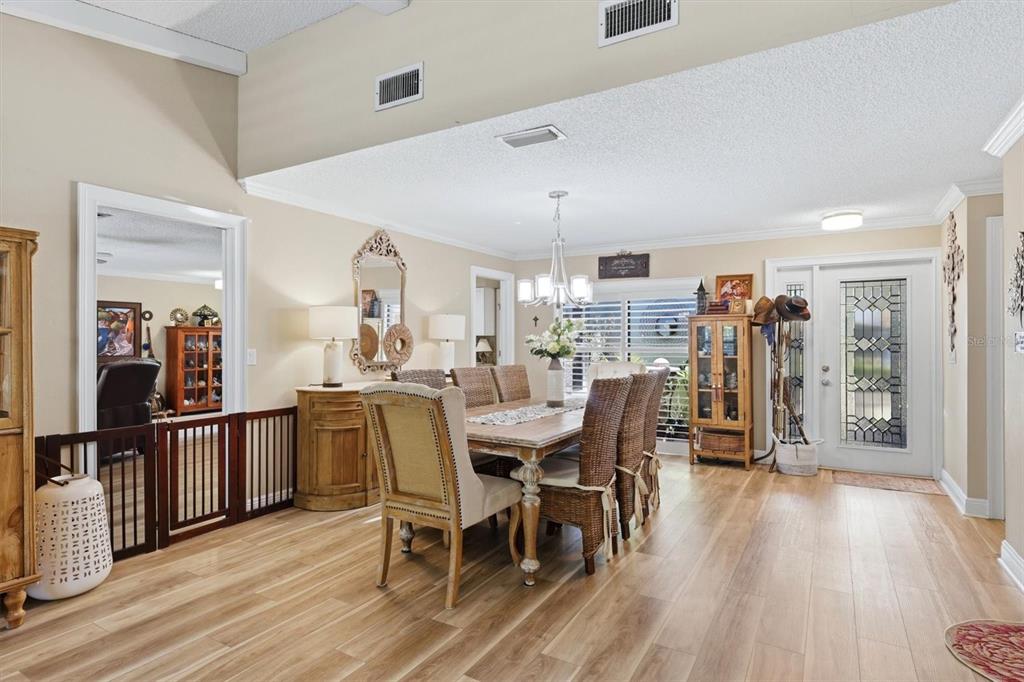 A dining room features a wooden table, wicker chairs, light wood flooring, and a front door — 3828 EASTON STREET, SARASOTA, FL